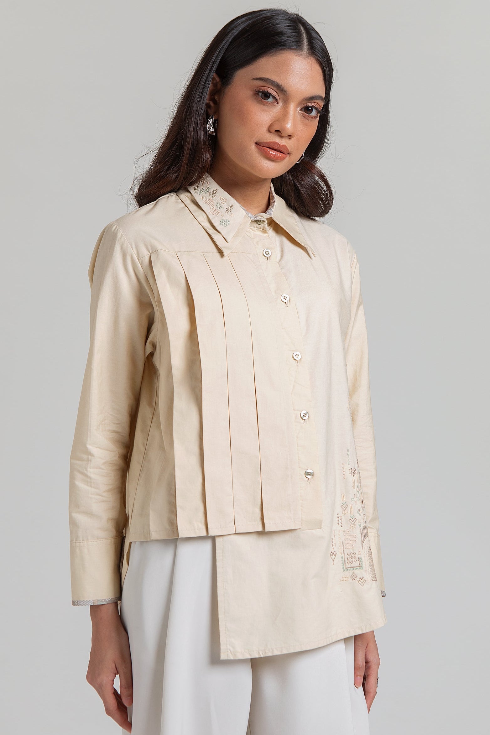 Diskon 15% atasan wanita lengan panjang premium berbahan 100% katun adem. Desain asimetris berlapis dengan detail lipit (pleats) dan aksen bordir yang elegan.