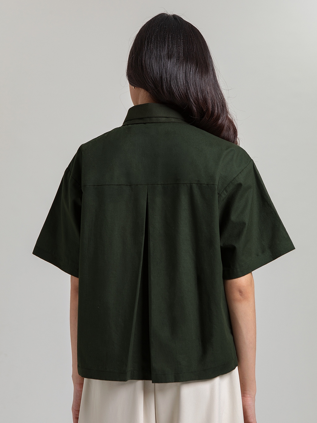 DISKON 15%. Atasan wanita kemeja lengan pendek premium dari bahan textured cotton yang adem dan busui-friendly. Desain asimetris modis dengan detail bordir saku artistik.